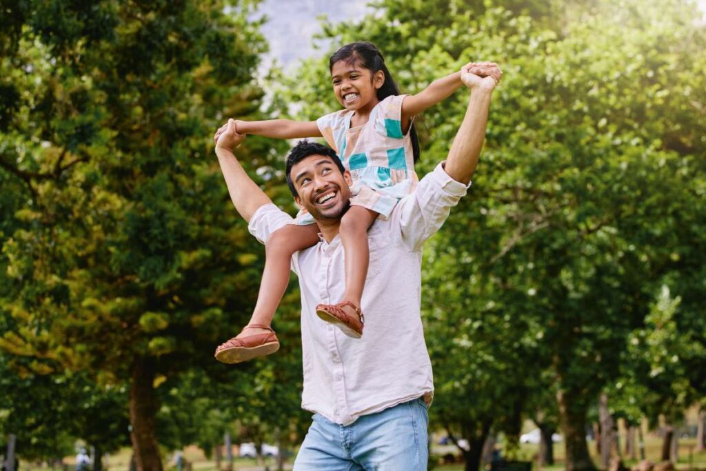 young father holding their daughter on their shoulders celebrating a healthy lifestyle