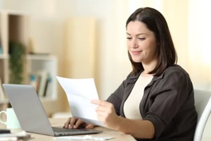 woman reading an ACA open enrollment letter using laptop at home